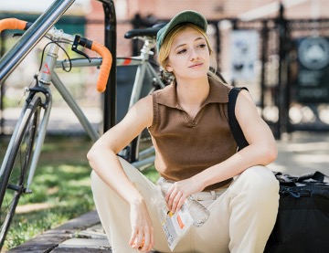 vrouw die zit naast fiets en water in haar hand heeft