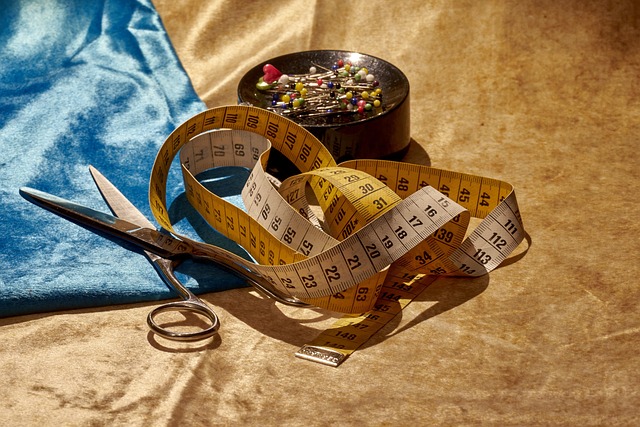 stof, schaar, meetlint en spelden om iets op maat te maken